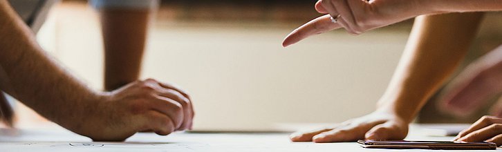Mehrere Hände. die gestikulieren. Außerdem ein Tablet zu sehen
