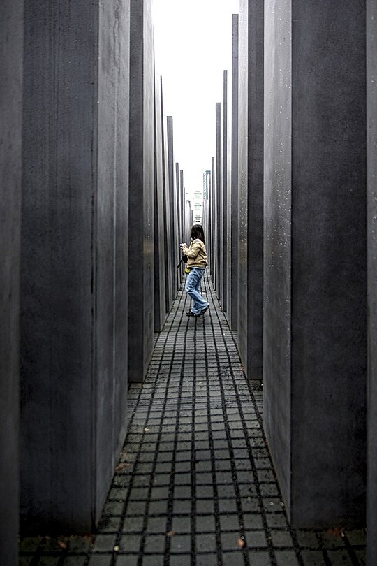 Person steht zwischen hohen Betonstelen in einer Gedenkstätte.